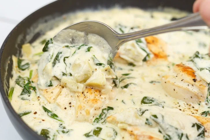 Delicious chicken in creamy sauce with spinach and artichokes served on a plate