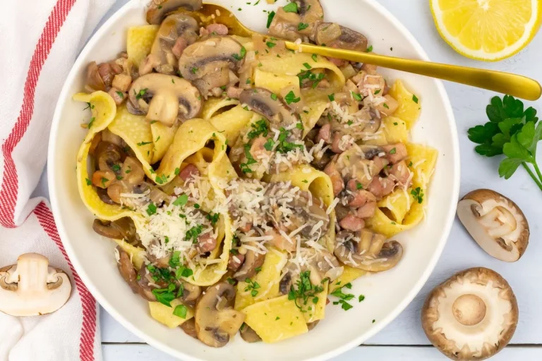 Bord met pappardelle, champignons en pancetta, een smaakvol Italiaans gerecht.