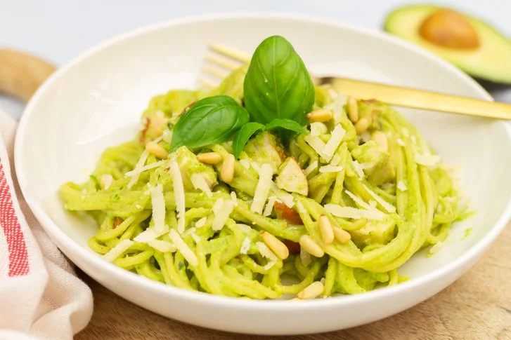 Pasta met avocadopesto en gerookte kip op een bord