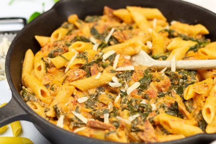 Pasta met spinazie en chorizo geserveerd in een kom