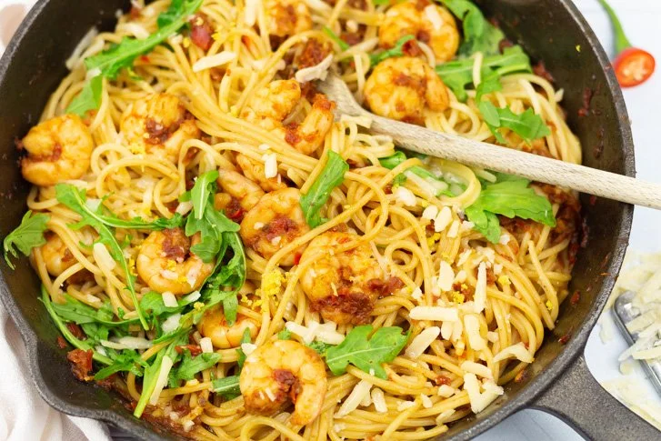 Heerlijke spaghetti met garnalen, geserveerd met verse kruiden.