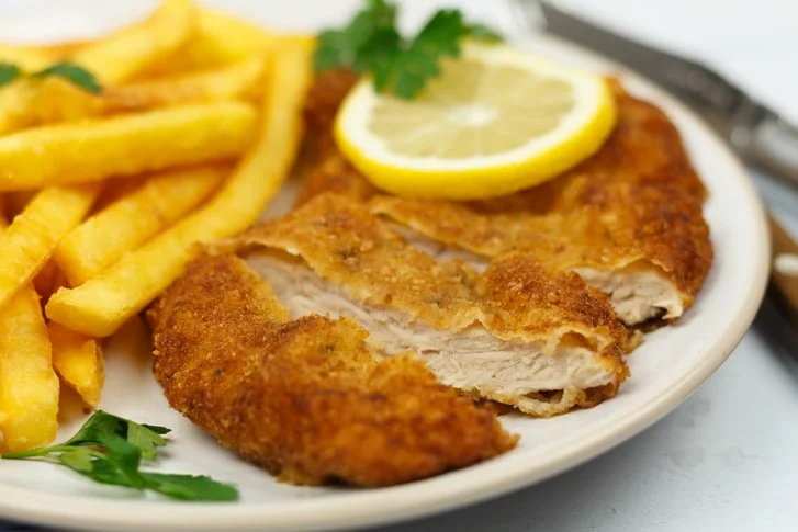 Gekruide Varkensschnitzel Wiener Art met een krokante korst op een bord.