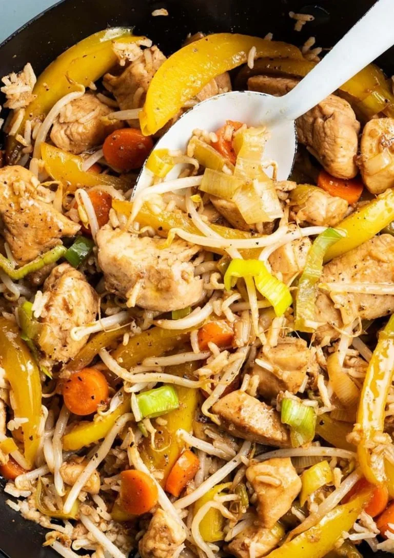 Authentieke wok met kippenblokjes, rijst en kleurrijke wokgroenten.