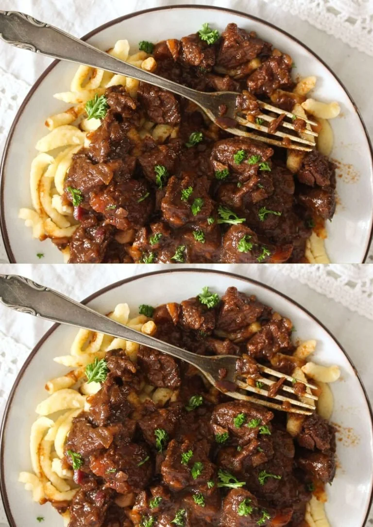 Een rijke Duitse Goulash geserveerd met vers brood en kruiden.