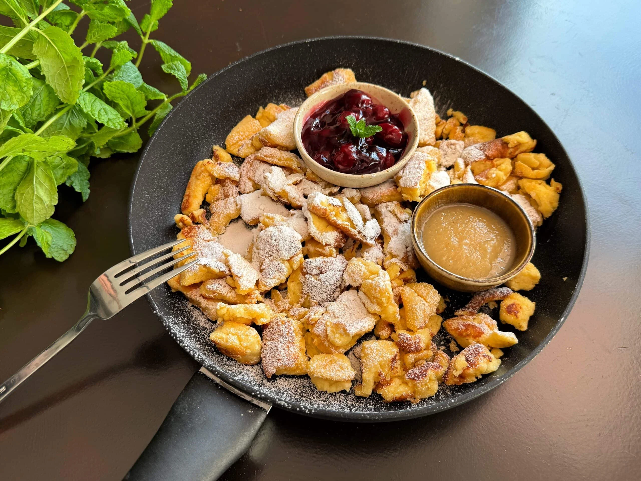 Heerlijke Kaiserschmarrn geserveerd met poedersuiker en fruit.
