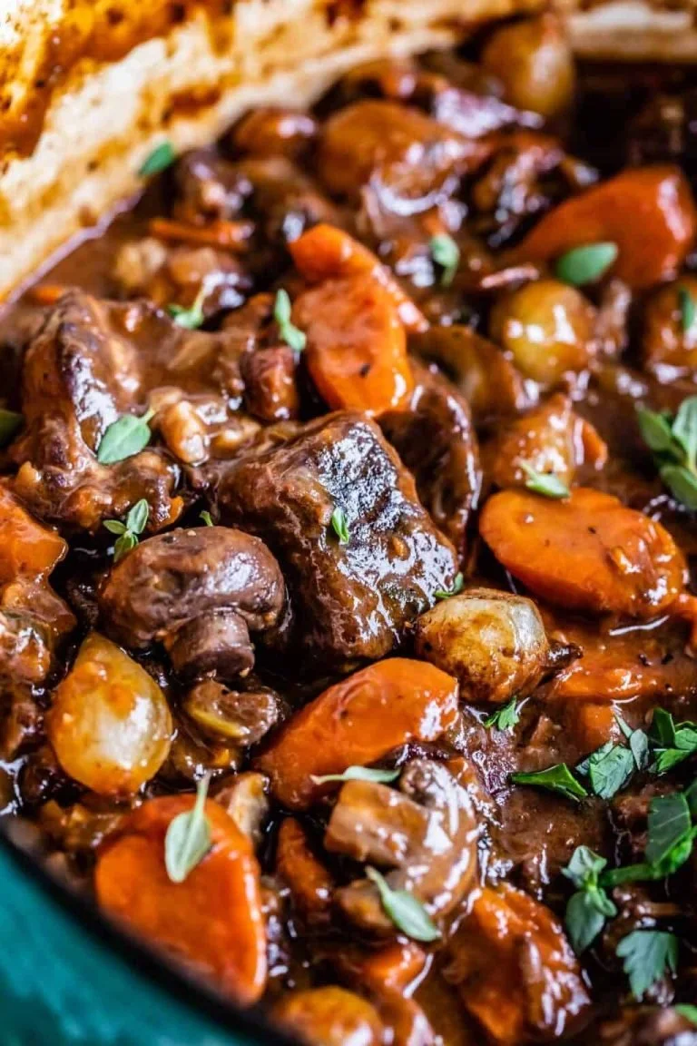 Klassieke Beef Bourguignon met groenten en rode wijn geserveerd in een stoofpot.