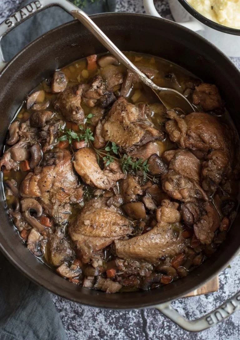Klassieke Franse Coq Au Vin met knoflookboter aardappelen op een bord