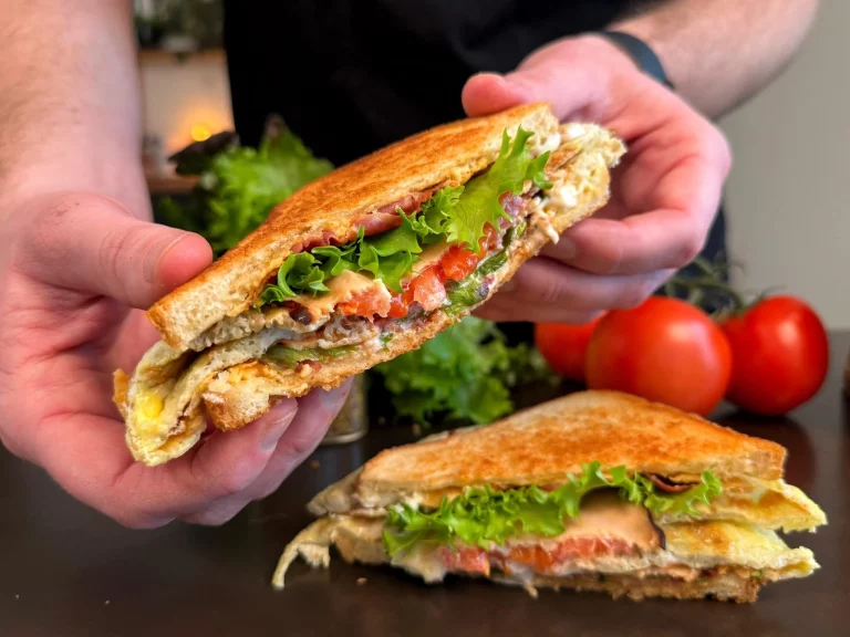 Snelle club sandwich met spek, kip en groenten op een bord.