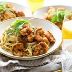 Linguine met garnalen geserveerd met verse kruiden en citroen.