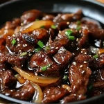 Geroosterd rundvlees met gekarameliseerde uien en sojasaus op een bord