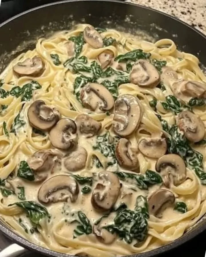 Pasta met spinazie, champignons en parmezaan op een bord