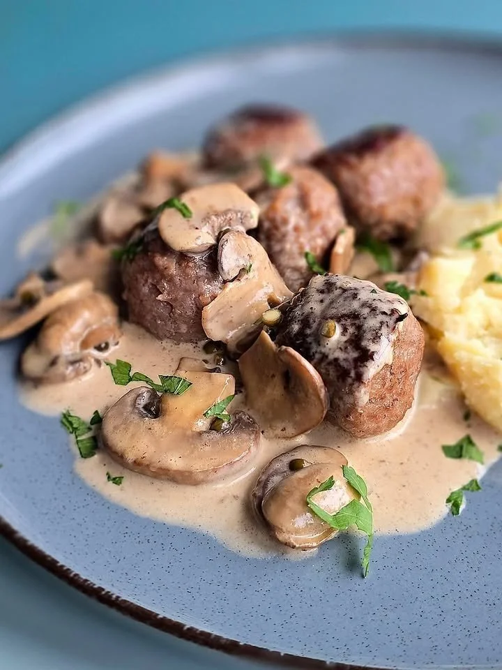 Balletjes in champignon-pepersaus op een bord geserveerd
