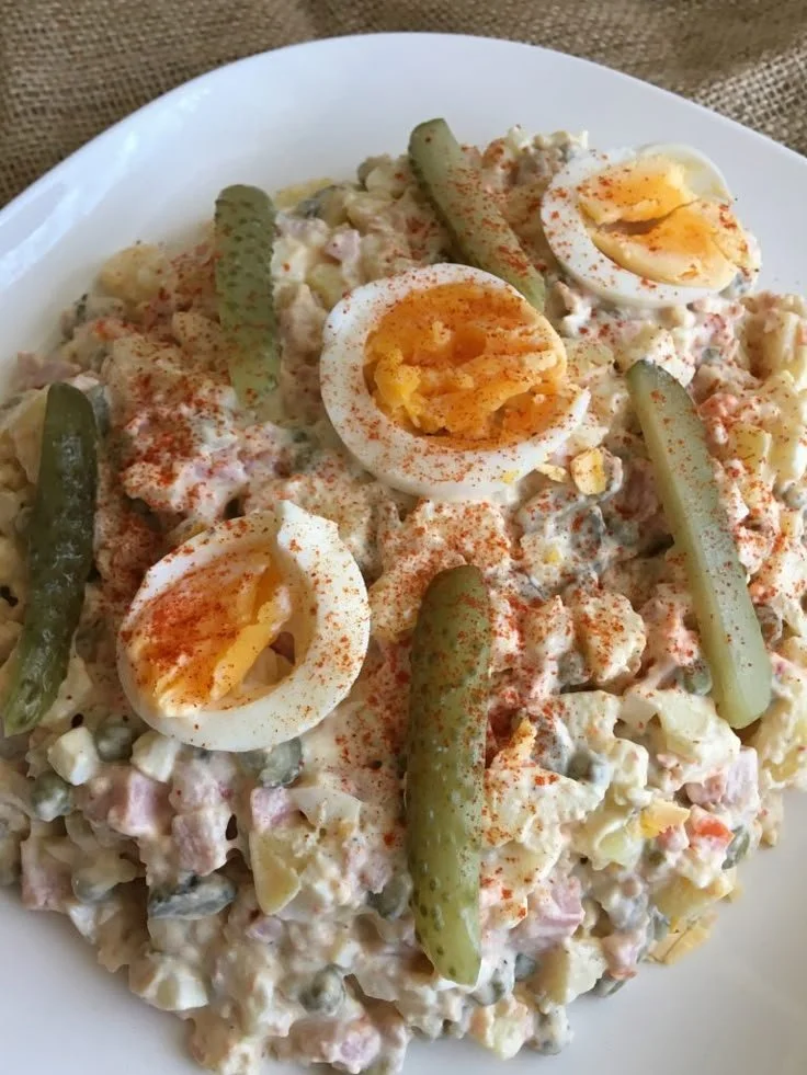Een heerlijke Huzarensalade met vlees, groenten en dressing op een bord.