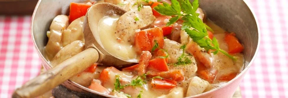 Kipstoofpotje met spekjes en rode paprika in een pan