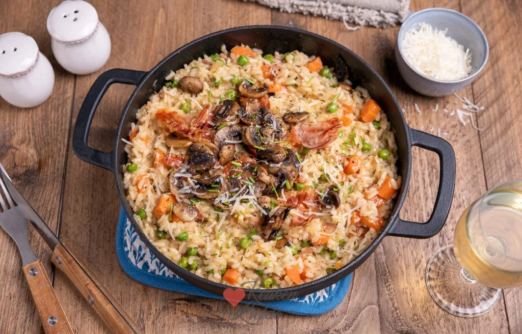Romige risotto met wortel, champignons en krokant spek op een bord